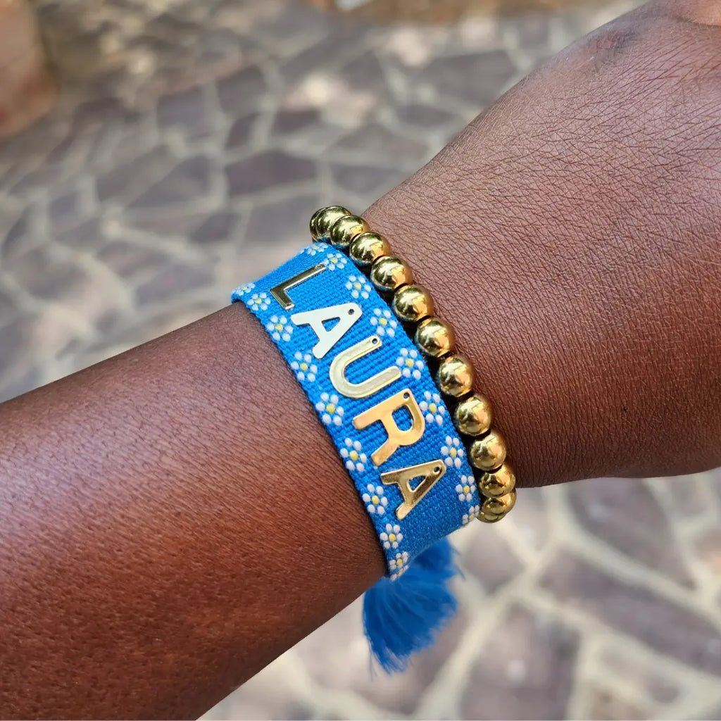 bracciale in filo blu con bordi con fiori bianchi, con nappa regolabile, personalizzato con nome in acciaio inox colore oro. Regalo personalizzato unisex per ogni occasione, anche per auto regalo. Regalo compleanno, Natale