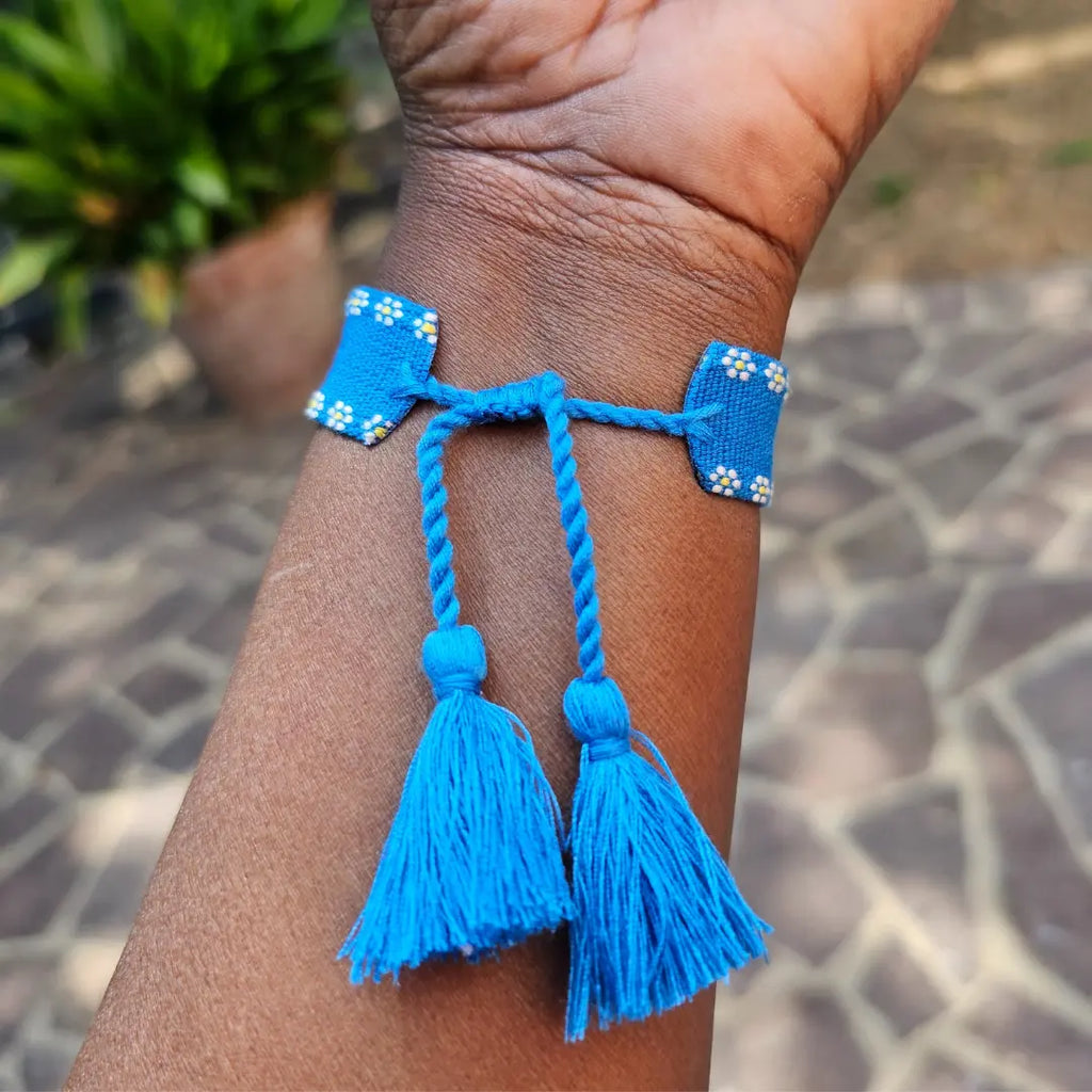 bracciale in filo blu con bordi con fiori bianchi, con nappa regolabile, personalizzato con nome in acciaio inox colore oro. Regalo personalizzato unisex per ogni occasione.