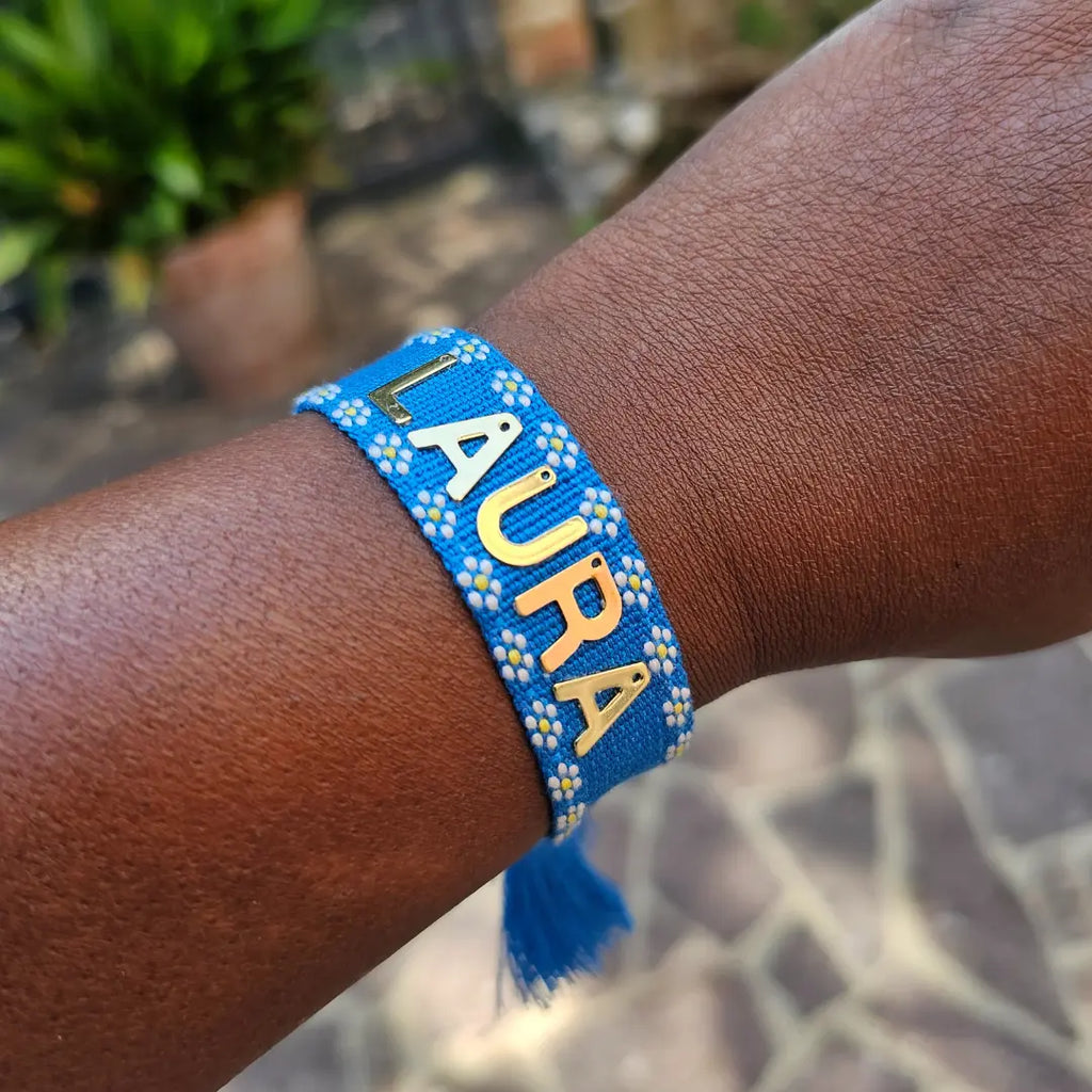 bracciale in filo blu con bordi con fiori bianchi, con nappa regolabile, personalizzato con nome in acciaio inox colore oro. Regalo personalizzato unisex per ogni occasione, anche per auto regalo, regalo per tutti outfit